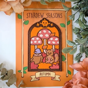 May include: A brown and orange embroidered patch featuring a squirrel, mushrooms, and leaves. The patch is framed in a brown arch with the text "Stardew Seasons" and "Autumn" on a brown and orange background.
