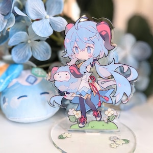 May include: A blue and white anime character figurine holding a small blue and white sheep. The figurine is standing on a clear acrylic base with white flowers.