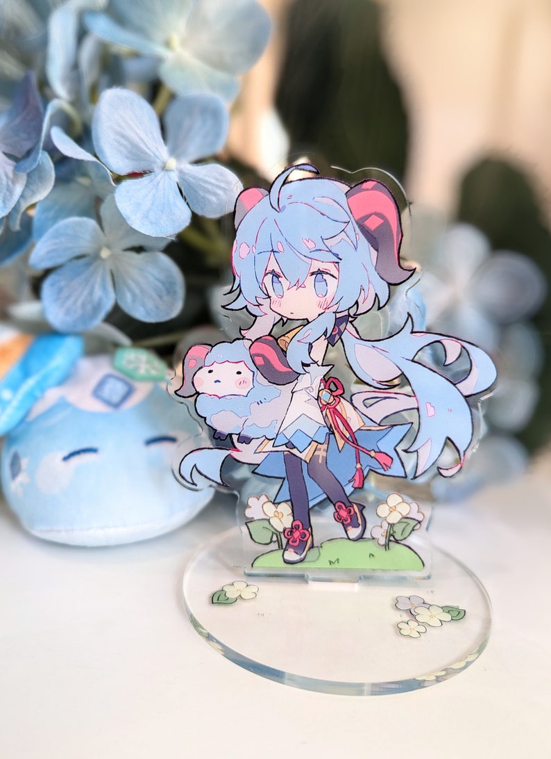 May include: A blue and white anime character figurine holding a small blue and white sheep. The figurine is standing on a clear acrylic base with white flowers.