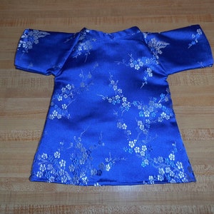 May include: A blue satin dress with a white floral pattern. The dress has short sleeves and a round neckline.