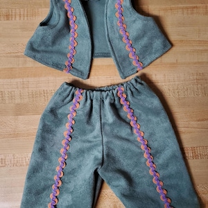 May include: A green suede vest and pants set with orange and purple trim. The vest has a V-neck and sleeveless design. The pants are long and have a straight leg.