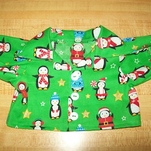 May include: A green button-up shirt with a penguin pattern. The penguins are wearing Santa hats, scarves, and candy canes. The shirt has a white collar and buttons.