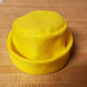 May include: A white ceramic mug with a black handle and the text "But First, Coffee" in a bold, black font. The mug is set against a blurred background, suggesting a cozy setting.