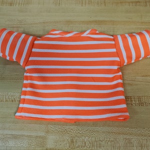 May include: Orange and white striped short-sleeved shirt with a crew neck.