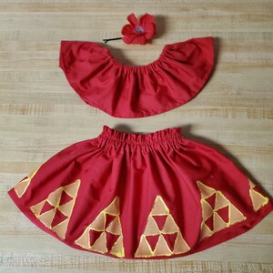 Op de afbeelding: Een rode rok met een gouden geometrisch patroon en een bijpassend rood topje met een gerimpelde halslijn. Een rode bloem is inbegrepen.