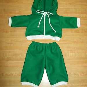 Könnte beinhalten: Ein grüner Kapuzenpullover mit weißen Kanten und einem weißen Kordelzug. Der Pullover wird mit einer grünen Hose kombiniert, die ebenfalls weiße Kanten hat.