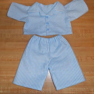 May include: A blue and white striped pyjama set. The top has short sleeves and a button-down front. The matching shorts have an elasticated waistband. The fabric is soft and lightweight, suitable for sleepwear.