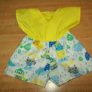 May include: A yellow sleeveless romper with a white and blue print featuring cartoon animals and raindrops.