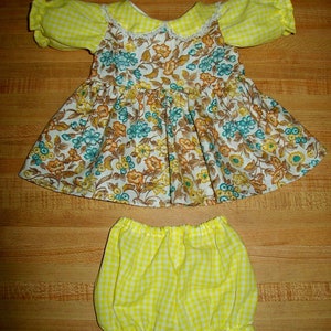 Może przedstawiać: Żółto-biała sukienka w kratę z kwiatowym nadrukiem i białym koronkowym kołnierzykiem. Sukienka jest zestawiona z pasującymi żółto-białymi spodenkami w kratę.