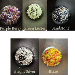 May include: Five small bowls filled with beads in various colors. The bowls are labeled "Purple Berry", "Green Luster", "Sandstone", "Bright Silver", and "Blaze". The beads are small and round, and the colors vary from purple and red to silver and yellow.