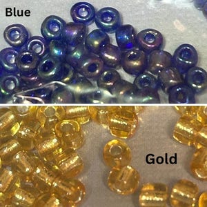 May include: Close-up of two groups of small beads. The top group is blue with iridescent highlights, and the word "Blue" is visible. The bottom group is gold, with the word "Gold" visible. These beads are suitable for jewelry making and crafts.