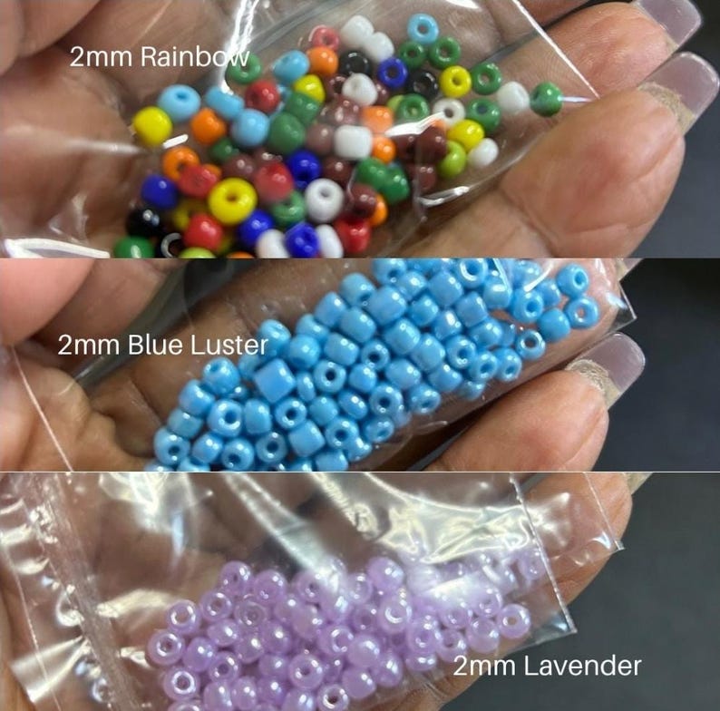 May include: Three small plastic bags filled with 2mm beads in rainbow, blue luster, and lavender colors. The rainbow beads are a mix of colors, the blue beads are a light blue, and the lavender beads are a soft purple. The text "2mm Rainbow", "2mm Blue Luster", and "2mm Lavender" are printed on the bags.