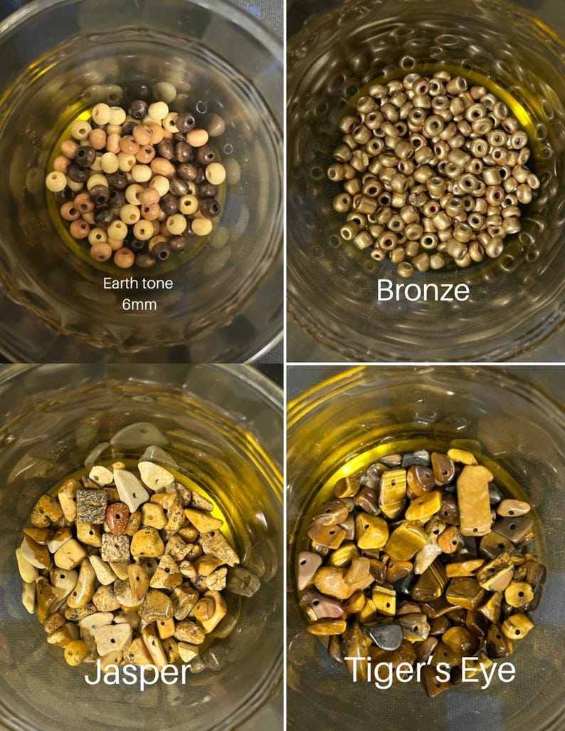 May include: Four glass jars filled with beads and stones. The top left jar contains earth tone beads, 6mm in size. The top right jar is filled with bronze beads. The bottom left jar contains jasper stones, and the bottom right jar has tiger's eye stones.