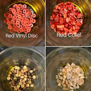 May include: Four glass jars filled with beads and stones. The jars contain red vinyl discs, red coral, earth tone 6mm beads, and sunstone. Text on the jars reads "Red Vinyl Disc", "Red Coral", "Earth Tone 6mm", and "Sunstone".