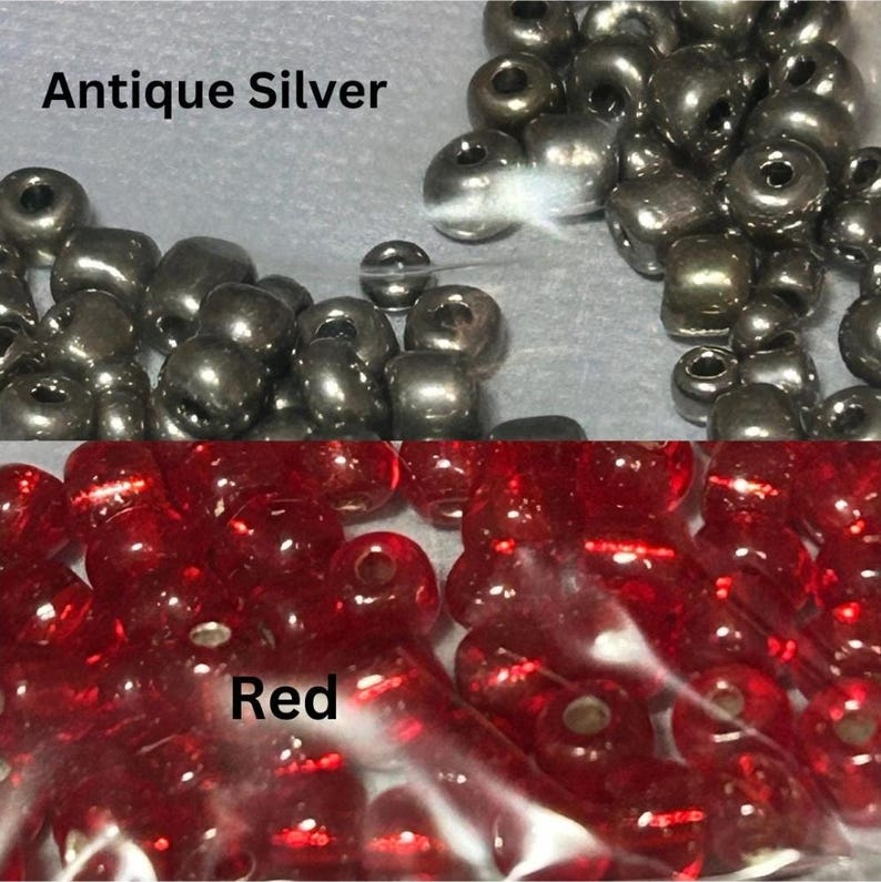 May include: Close-up of two groups of beads. The top section features antique silver beads, while the bottom section displays red beads. The text "Antique Silver" and "Red" are visible. These beads are suitable for jewelry making and crafts.