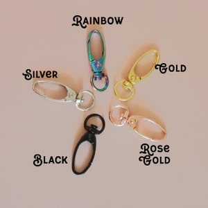 May include: Five different colored metal lobster clasps, including rainbow, silver, gold, rose gold, and black.