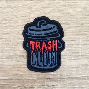 May include: Embroidered patch with a dark grey trash can design and a black border. The word "TRASH" is written in dripping red letters across the front of the trash can. The word "LID" is written below "TRASH".