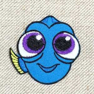 Può includere: Toppa ricamata raffigurante un pesce dei cartoni animati con grandi occhi espressivi. Il pesce è principalmente blu con accenti viola e bianchi intorno agli occhi e una pinna gialla. La toppa è da stirare o cucire.