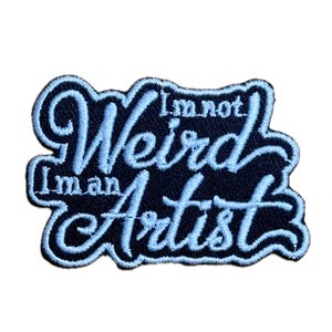 Puede incluir: Parche bordado con el texto "I'm not Weird I'm an Artist" en escritura azul claro sobre un fondo azul oscuro. El parche tiene un borde azul claro.