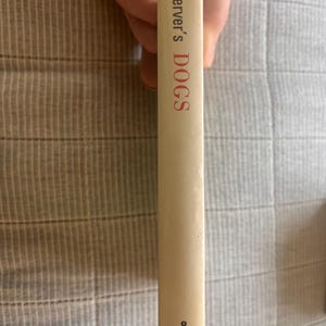 May include: A book spine with the title "Observer's DOGS" in red lettering. The book is off-white with the number "8" and the publisher "WARNE" at the bottom. The book is held by a person.