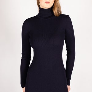 Op de afbeelding: Een donkerblauwe trui-jurk met een geribbelde textuur.