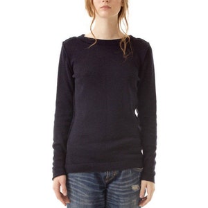 May include: A long-sleeved navy blue crew neck sweater paired with blue denim jeans featuring a distressed wash and cuffed hems, worn with black ankle boots. The sweater has a simple knit texture and the jeans show faded whiskering details.
