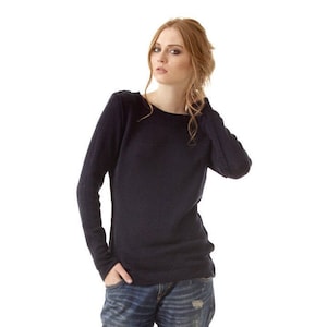 May include: A long-sleeved navy blue sweater with a round neckline paired with blue denim jeans featuring a distressed finish and rolled cuffs, complemented by black ankle boots with a pointed toe and a slim heel.
