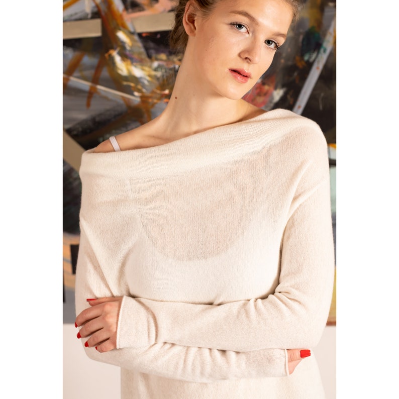 May include: A white off-the-shoulder sweater with long sleeves. The sweater is made of a soft, lightweight material and has a relaxed fit.