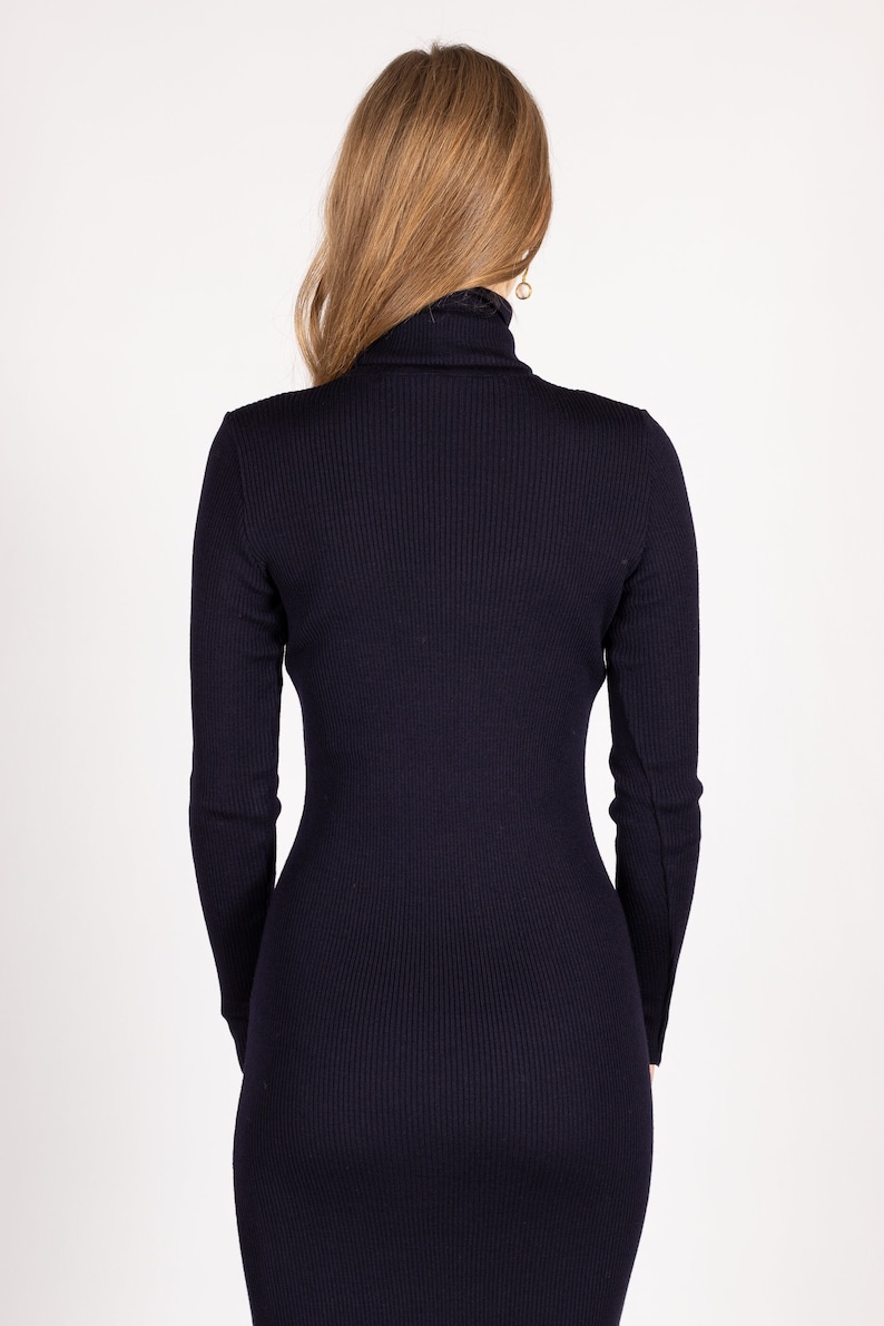 Op de afbeelding: Een lange, marineblauwe geribbelde trui met hoge hals.