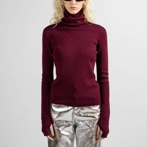 Burgundy red wool sweater featuring a high neck and soft merino wool texture.