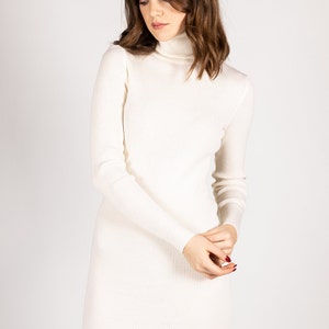 K&ouml;nnte beinhalten: Ein wei&szlig;es geripptes Rollkragenpulloverkleid. Das Kleid ist lang&auml;rmelig und hat eine figurbetonte Silhouette.