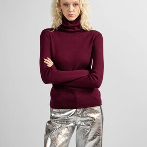 Full-body view of a red merino wool turtleneck sweater styled with a minimalist look.