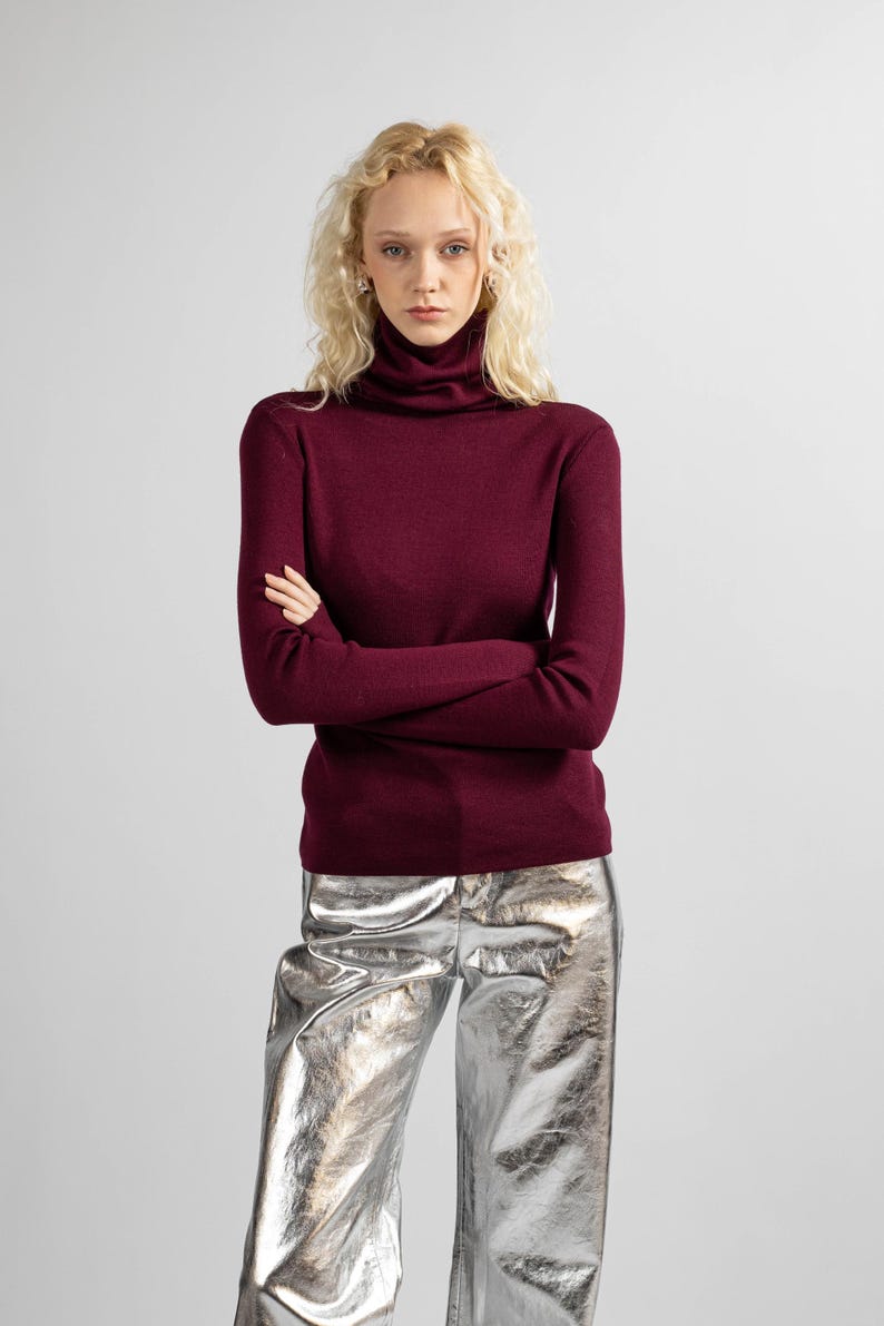 Full-body view of a red merino wool turtleneck sweater styled with a minimalist look.
