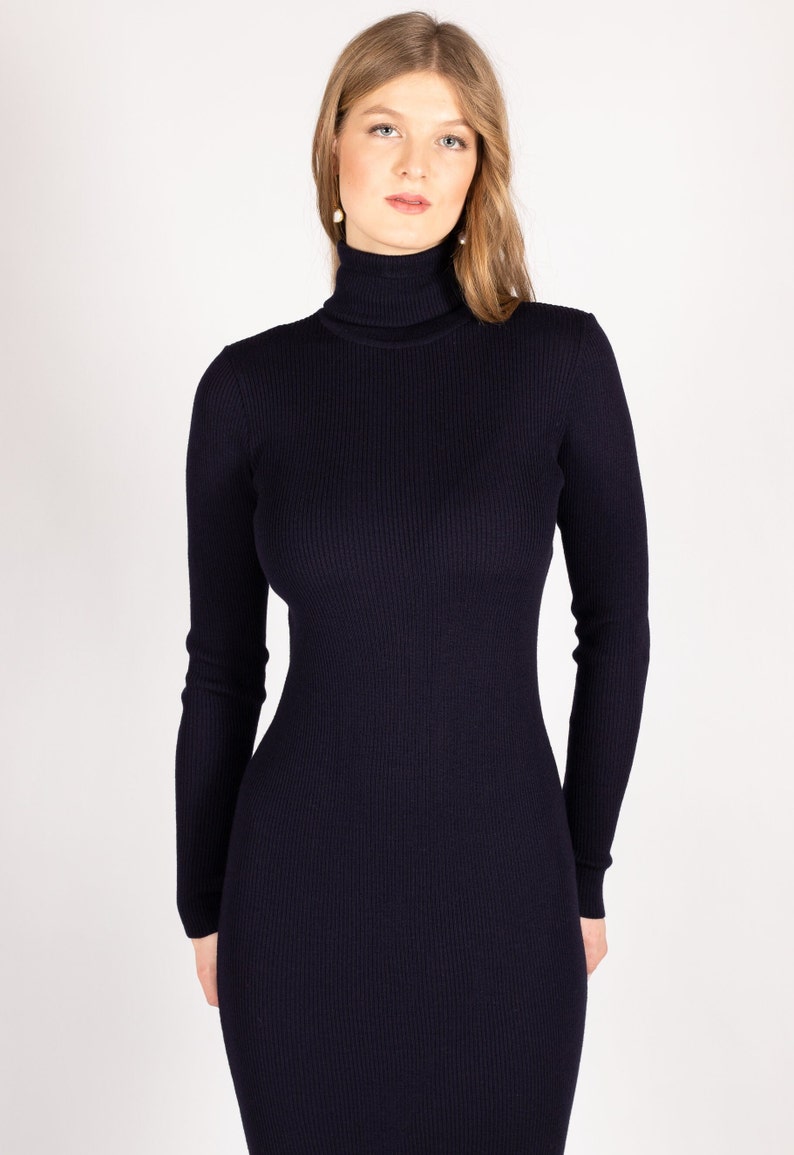 Op de afbeelding: Een donkerblauwe trui-jurk met een geribbelde textuur.