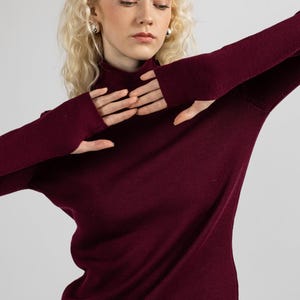 Elegant burgundy merino sweater with thumbholes, perfect for cooler weather.