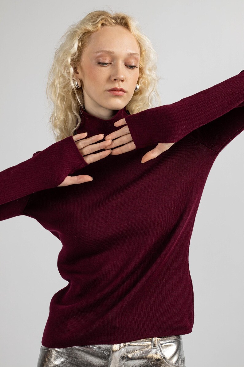 Elegant burgundy merino sweater with thumbholes, perfect for cooler weather.