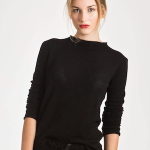 Puede incluir: Una camisa negra de manga larga con cuello alto.