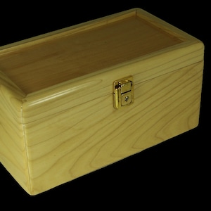 May include: A wooden box with a hinged lid and a brass latch. The box is made of light wood with a natural finish.