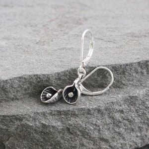 May include: Silver dangle earrings with a floral design. The earrings are made of sterling silver and have a delicate, feminine look.