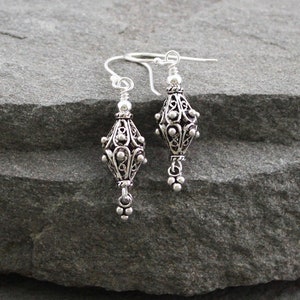 May include: A pair of silver filigree earrings with a teardrop-shaped design. The earrings have a delicate, intricate pattern and are perfect for adding a touch of elegance to any outfit.