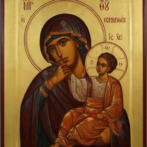 Può includere: Un'icona che rappresenta la Vergine Maria che tiene in braccio il Bambino Gesù. L'icona è dipinta in uno stile tradizionale con accenti dorati e il testo "MP OY ПАРАМΥΘΙΑ IC XC" in greco.