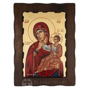 Può includere: Icona religiosa raffigurante la Vergine Maria e il Bambino Gesù, su sfondo dorato. Le figure sono vestite con abiti rossi e blu, incorniciate da un bordo in legno scuro. L'icona include testo greco.