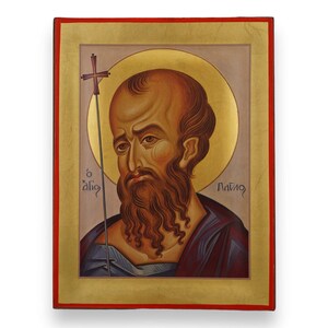 May include: A religious icon featuring a portrait of a man with a long brown beard and a bald head, surrounded by a gold halo. He holds a staff with a cross. The icon has a gold border with a red trim.