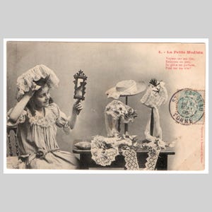 Cartolina fotografica d'epoca - Una ragazza prova dei cappelli in stile edoardiano - Antica cartolina d'auguri francese Bergeret rppc del 1906