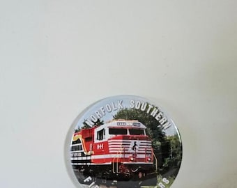 May include: A round button featuring a red and white Norfolk Southern train engine on a track. The text "Norfolk Southern First Responders" is around the edge of the button.