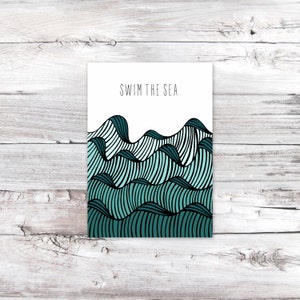 May include: A white card with the text "SWIM THE SEA" printed in black. The card features a graphic of teal blue and black waves.