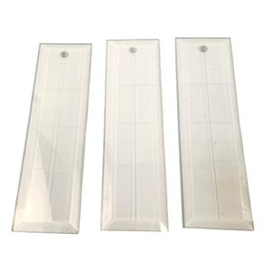 May include: Three rectangular, clear glass ornaments with a grid pattern and a small hole at the top for hanging. The ornaments are arranged vertically against a white background.