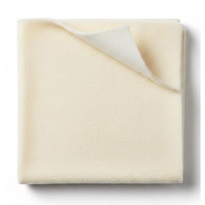 May include: A square, off-white felt fabric piece with a smooth, matte texture. The material is folded at the top right corner, revealing the same solid, light cream color on the underside. The edges are straight and clean, showing a uniform thickness.