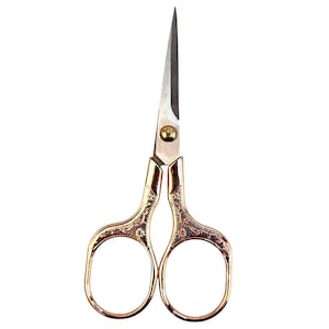 May include: Small, gold-colored embroidery scissors with a decorative floral pattern on the handles. The blades are silver and pointed. The scissors are designed for precision cutting in needlework and crafting projects.