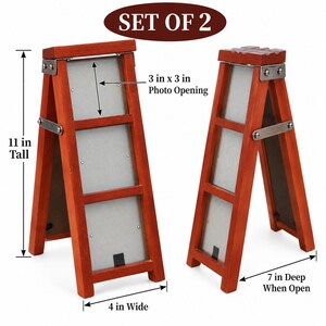 May include: A set of two wooden ladder-style picture frames with a reddish-brown finish and silver metal hinges. Each frame is 11 inches tall, 4 inches wide, and 7 inches deep when open, featuring a 3 inch by 3 inch photo opening.